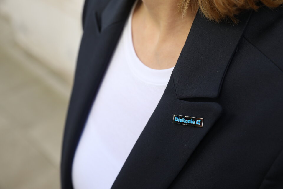 Stellenangebote Nahaufnahme eines Diakonie-Pins auf einem blauen Jacket