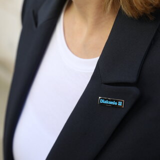 Stellenangebote Nahaufnahme eines Diakonie-Pins auf einem blauen Jacket