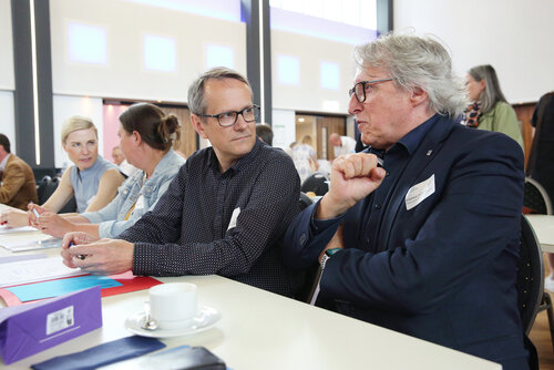 Zwei Teilnehmende der Mitgliederversammlung im Gespräch