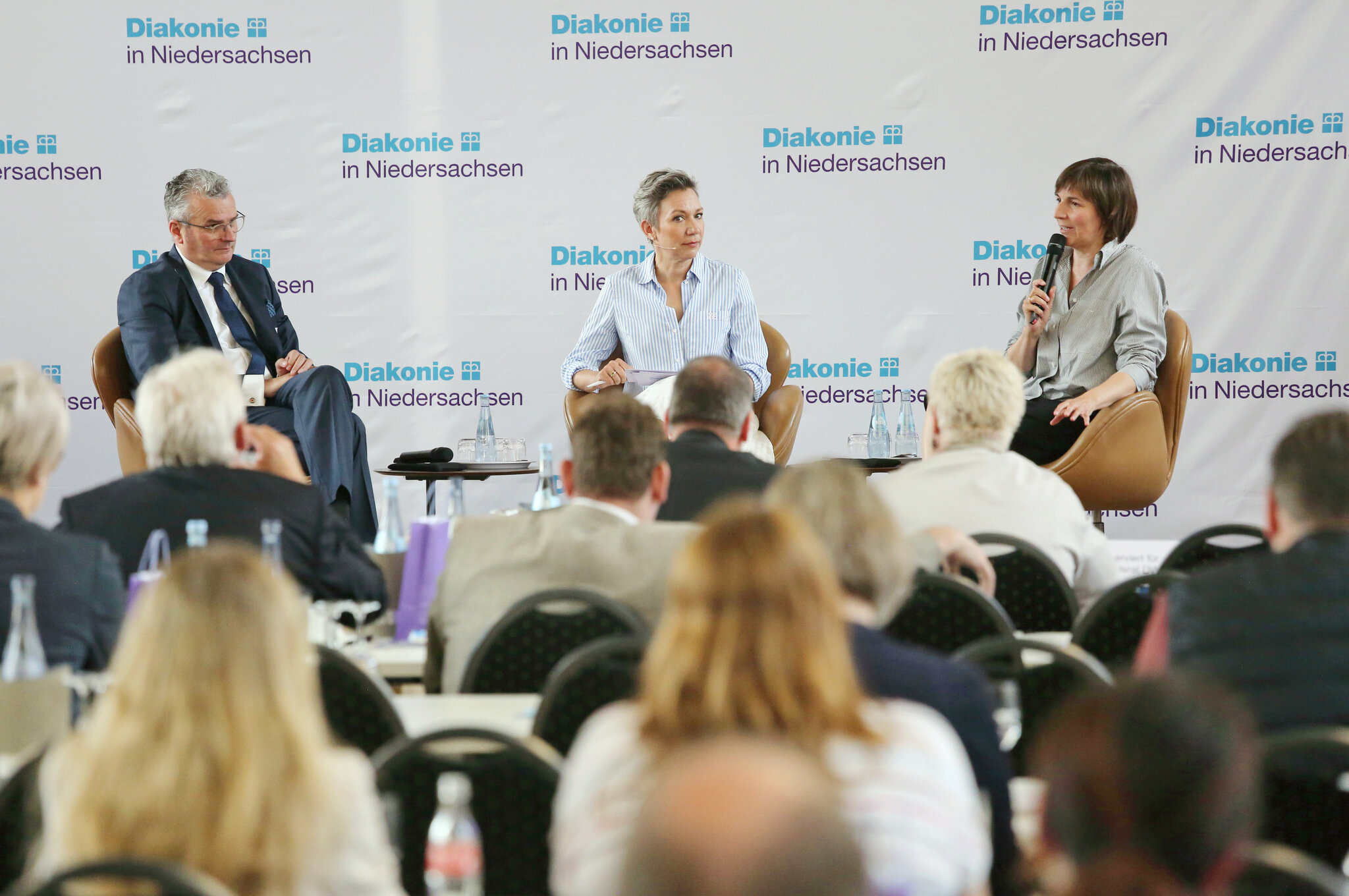 Hans-Joachim Lenke, Christina von Saß, Mareike Lotte Wulf sitzen auf dem Podium bei der Mitgliederversammlung