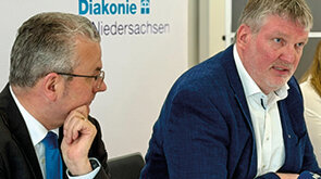 Hans-Joachim Lenke, Vorstandssprecher der Diakonie in Niedersachsen; Wolfgang Vorwerk, Vorstand Leinerstift e.V. sitzen bei der Pressekonferenz an einem Tisch nebeneinander