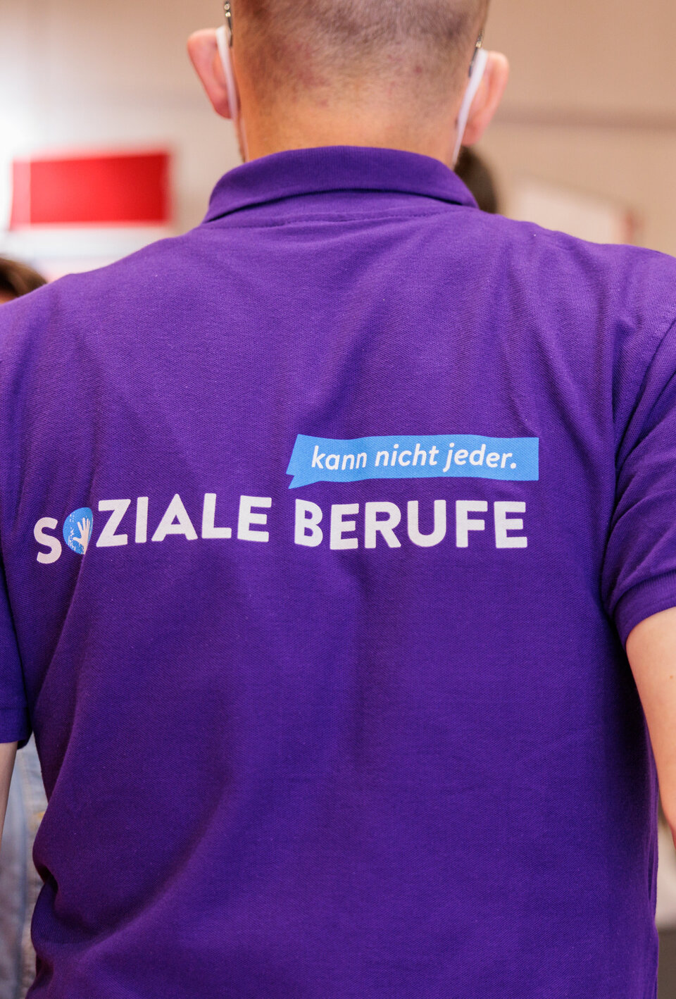 Ein Mensch von hinten, auf seinem T-Shirt steht "Soziale Berufe - kann nicht jeder"