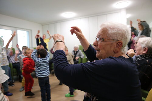 Ältere Menschen und Kita-Kinder tanzen zusammen