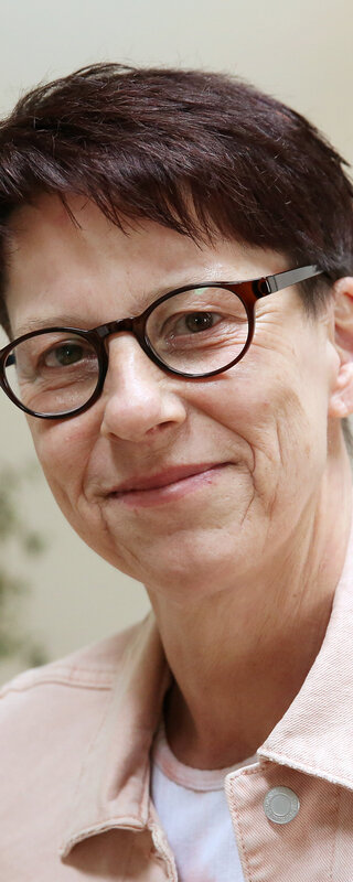 Alexandra B. schaut freundlich in die Kamera. Sie steht in einem Büro.