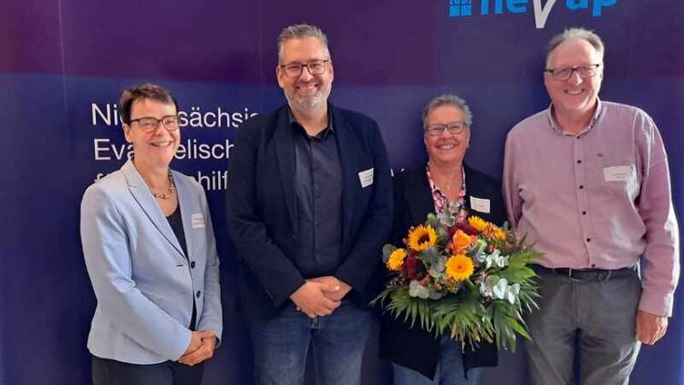 Stefanie Schwinge Fahlberg, Jens Wulfekammer, Jutta Schulte, Frank Pipenbrink stehen nebeneinander vor einer Wand auf der NEVAP steht und schauen freundlich in die Kamera